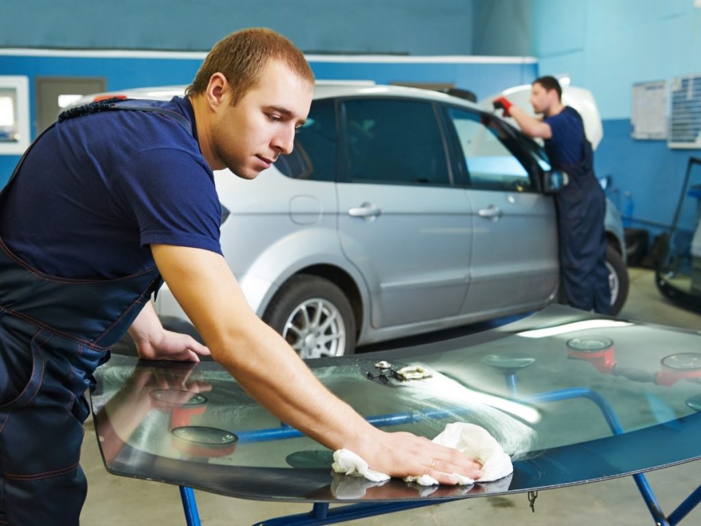 Worker cleaning a windshield before installation at an affordable auto glass repair shop in Evergreen Lawn