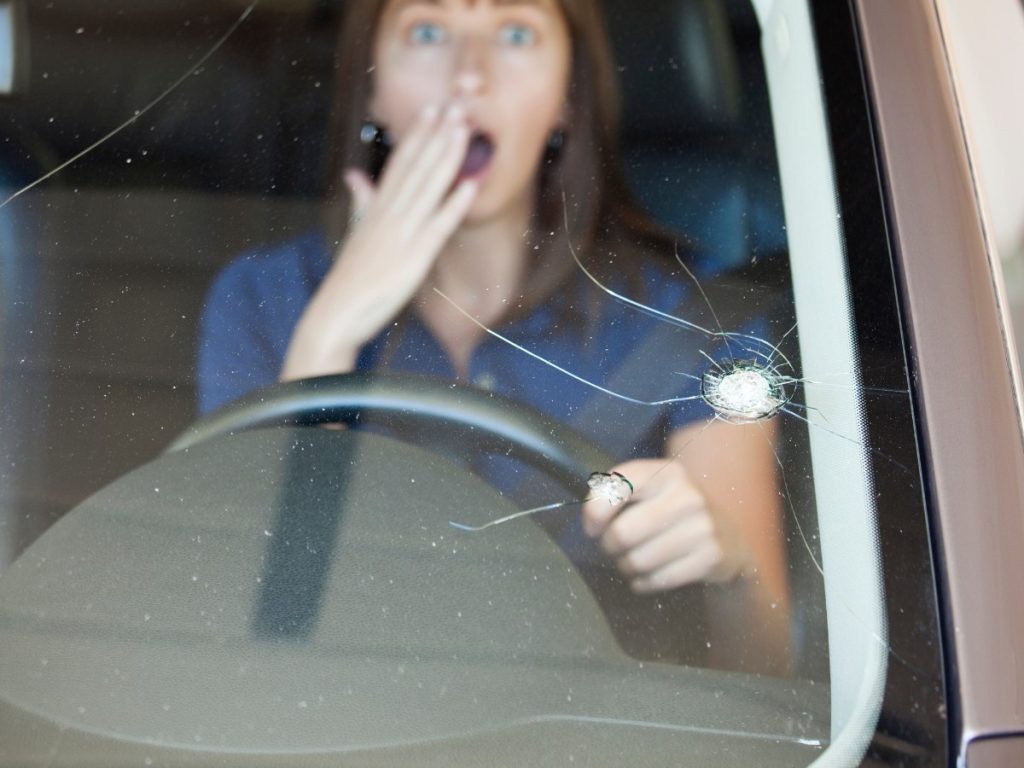 chipped windshield repair in boyd-booth, a surprised woman looks at a shattered car windshield