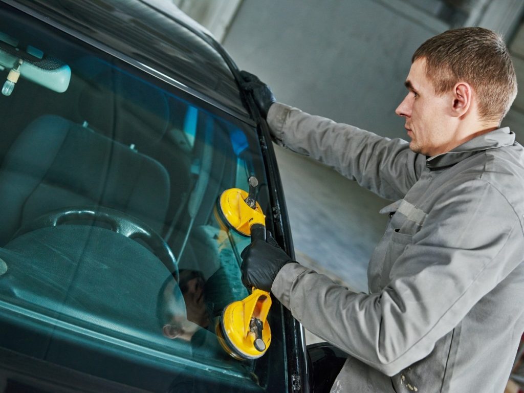 A technician at a local auto glass repair shop in Evergreen Lawn using a suction cup to remove a windshield