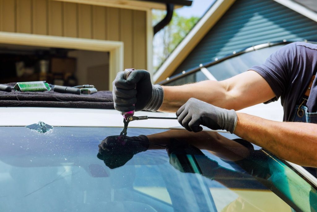 Worker repairing a cracked windshield with tools for Mobile Windshield Repair Baltimore, offering on-site auto glass fixes.