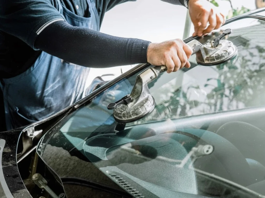 Mechanic installing a windshield with suction cups at a top Auto Glass Fix Baltimore shop, offering expert glass replacement services.