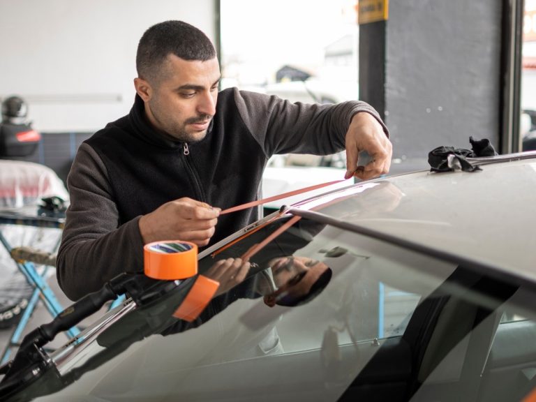 a technician at an auto glass repair shop in Baltimore using tape to seal a windshield