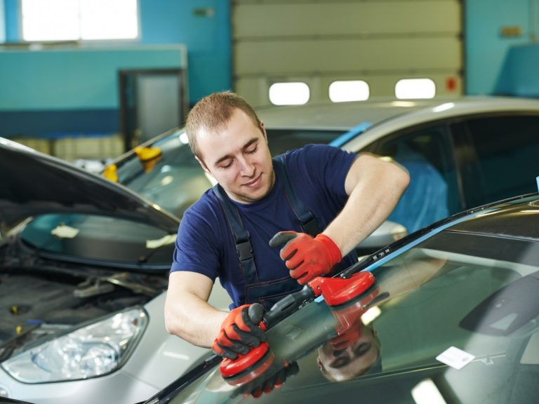 Technician using suction cups to install a new windshield, illustrating professional auto glass replacement in Baltimore
