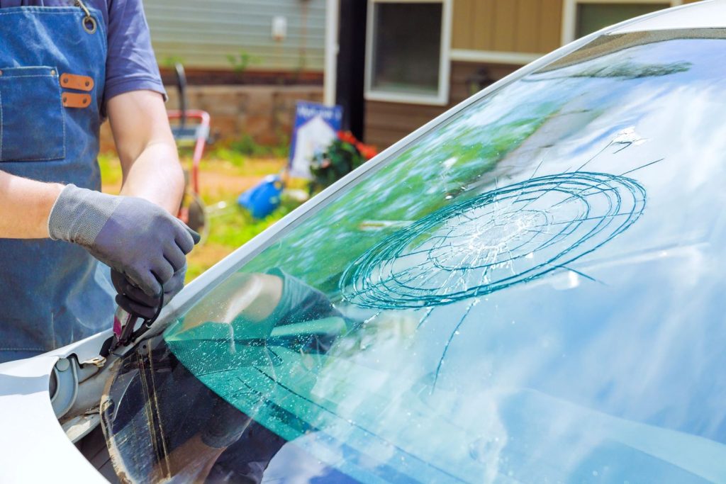 A technician repairs a cracked car windshield for auto glass fix Baltimore, working outdoors on a sunny day.