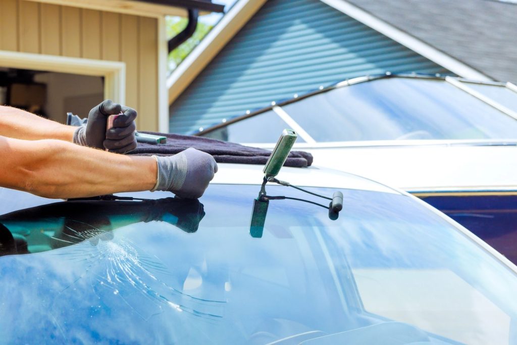 A technician repairs a cracked car windshield for auto glass fix Baltimore, working outside a home.