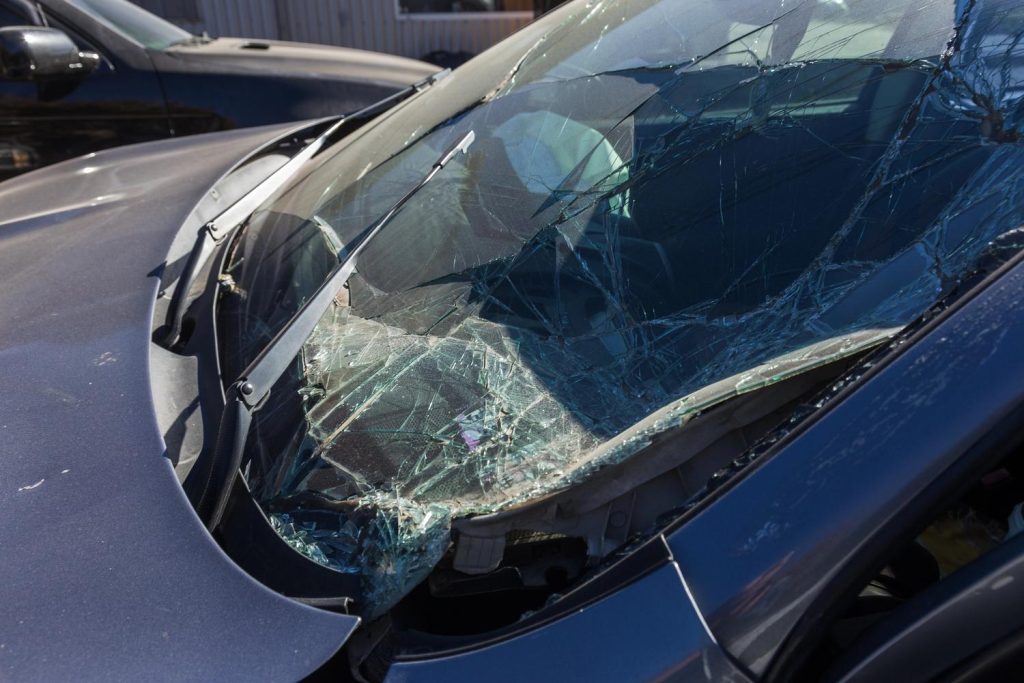 Close-up of severely cracked and shattered car windshield on blue vehicle, highlighting the need for expert windshield repair service in Baltimore to restore safety.