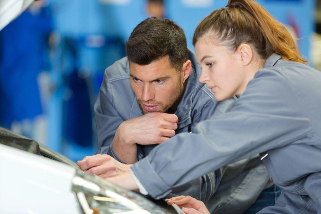 Experienced mechanics inspecting a car hood at a trusted windshield repair service in Baltimore.