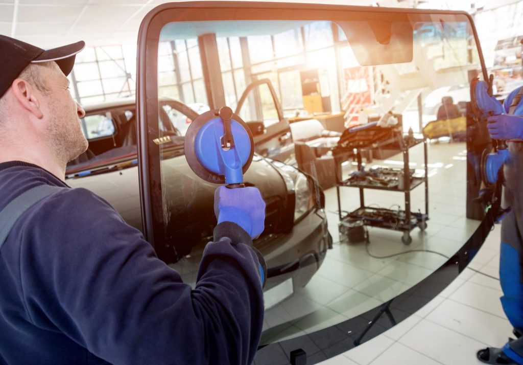 Technician installing a new windshield with tools at a professional windshield repair service in Baltimore.