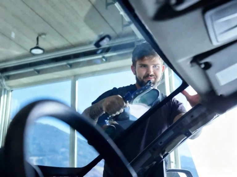 Technician performing mobile auto glass repair in Baltimore using professional tools on vehicle windshield.