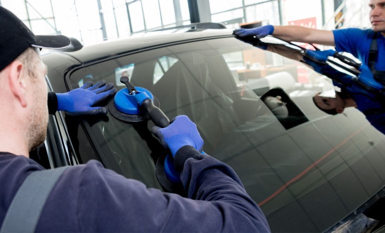 Auto glass experts using suction cups for secure rear windshield fix Baltimore installation.