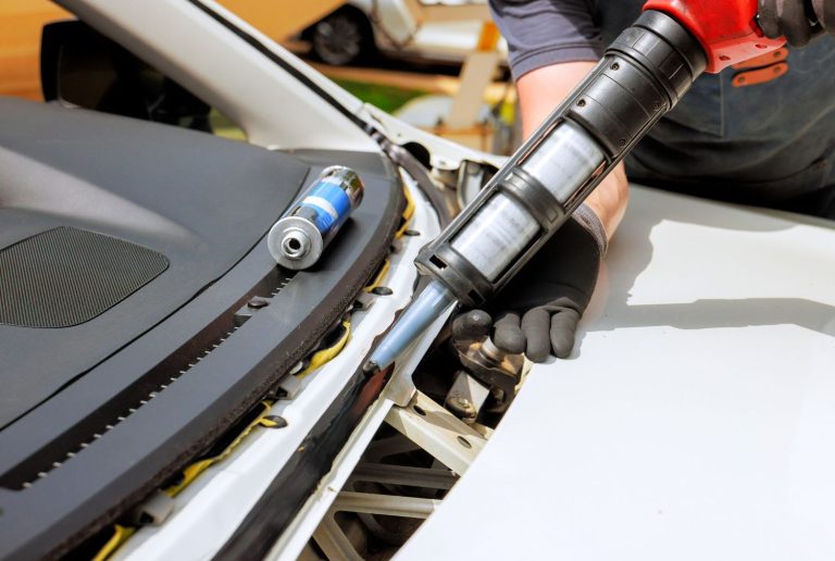 Close-up of a worker applying adhesive sealant for a quick car windshield fix Baltimore replacement.