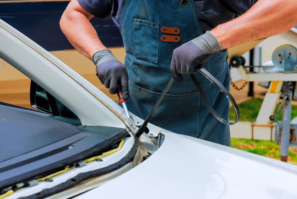 Mechanic removing the seal and trim for a professional car windshield fix Baltimore auto glass service.