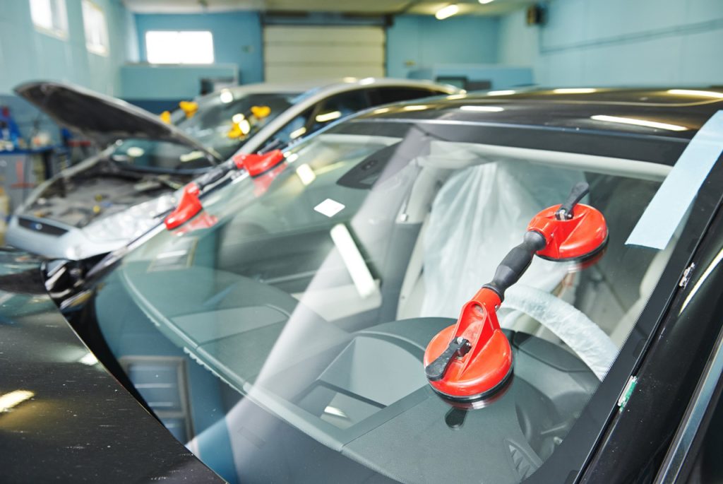 Professional auto glass fix Baltimore technicians using heavy duty red suction cups to install a new windshield.