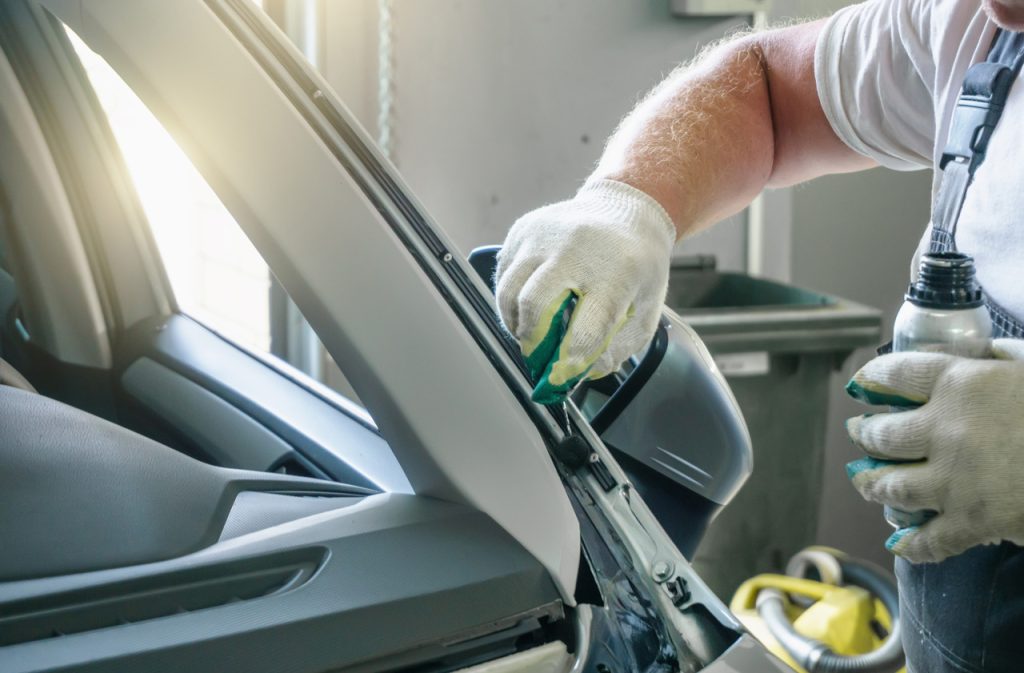Expert at an auto glass company Baltimore performing prep work on a vehicle frame before installing a new windshield.