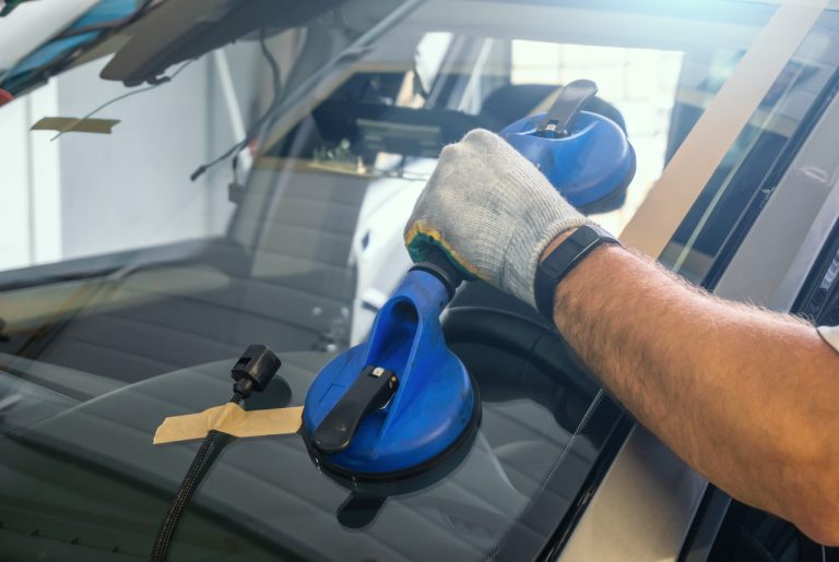 Skilled installer at an auto glass company Baltimore using heavy-duty suction cups to secure a new glass windshield.