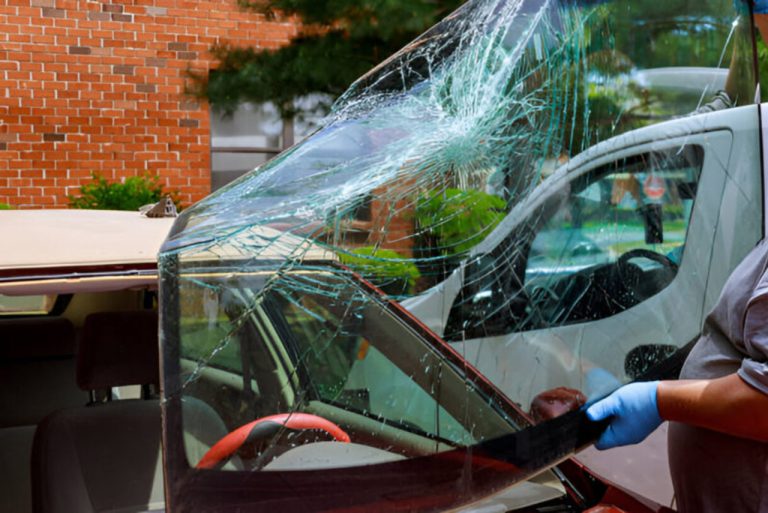 Mobile auto glass repair Baltimore specialist carefully lifting a cracked windshield during a mobile car glass fix.