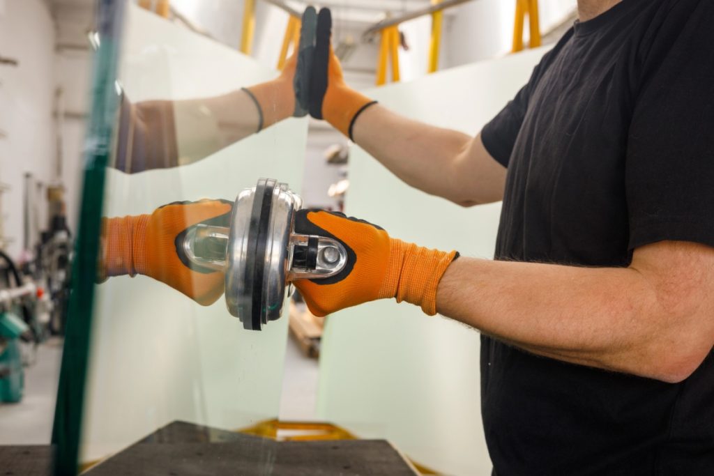 Professional auto glass replacement Baltimore technician using suction tools to handle a large clear glass pane safely.