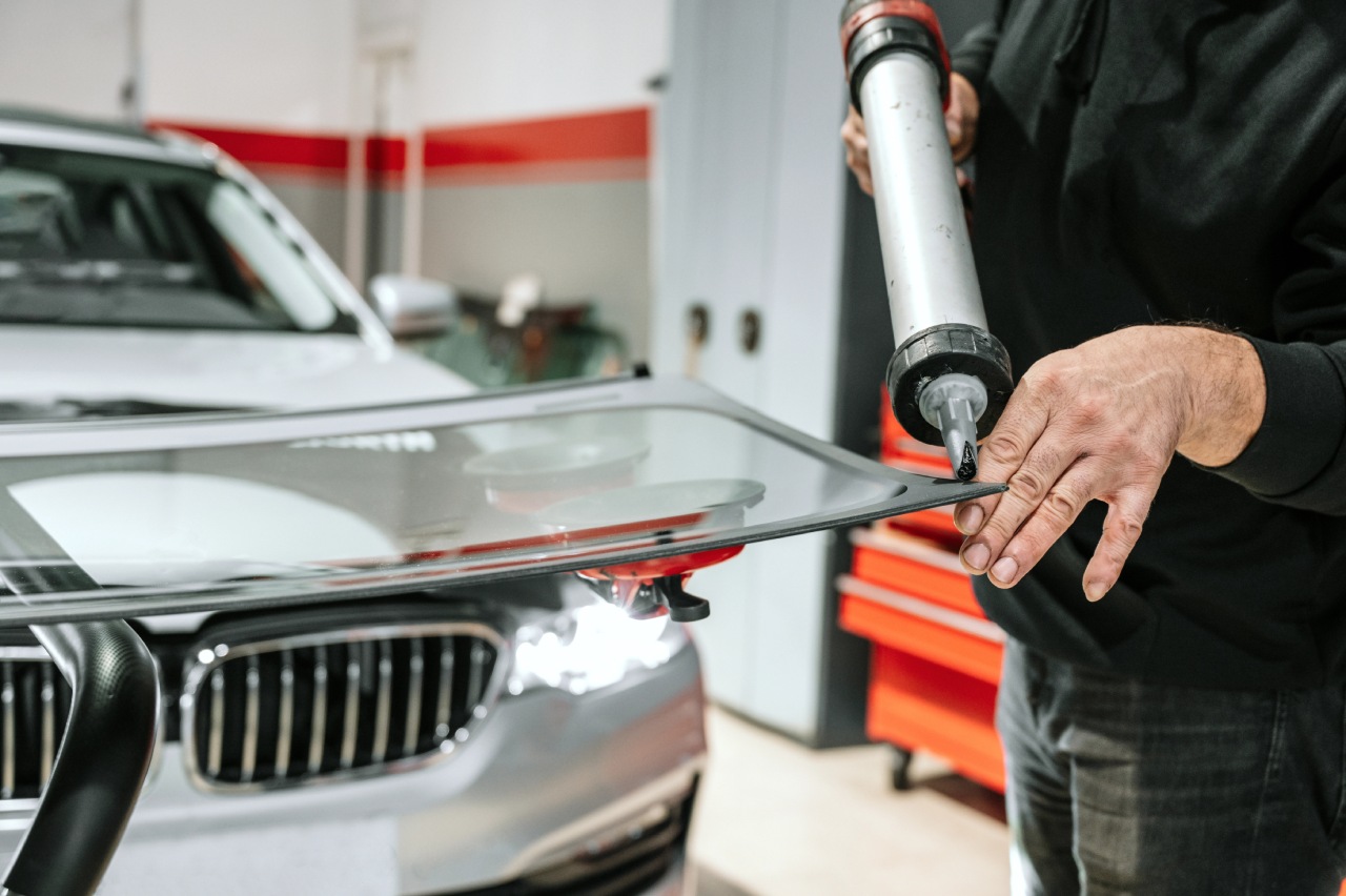 Technician at an auto glass company Baltimore applies black adhesive sealant to a car window for a secure replacement fit.