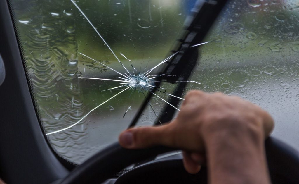 Rain hitting a cracked windshield while driving, needing an emergency auto glass repair service Baltimore for safety.