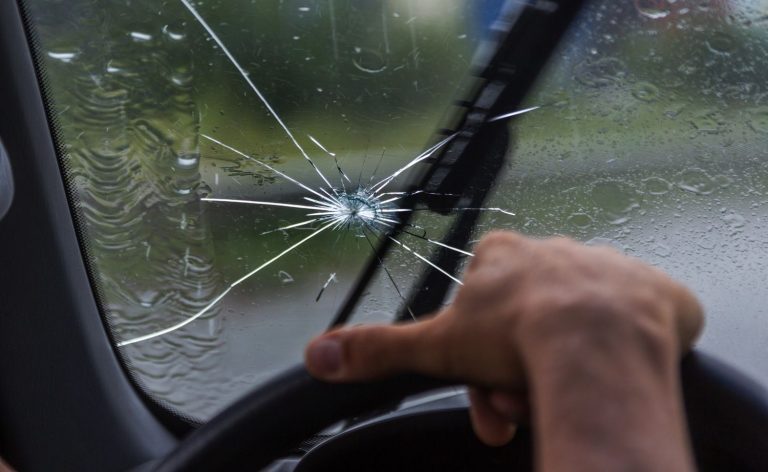 Rain hitting a cracked windshield while driving, needing an emergency auto glass repair service Baltimore for safety.