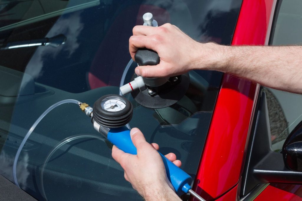 Professional technician uses specialized vacuum tools for auto glass repair Baltimore to fix a car windshield.
