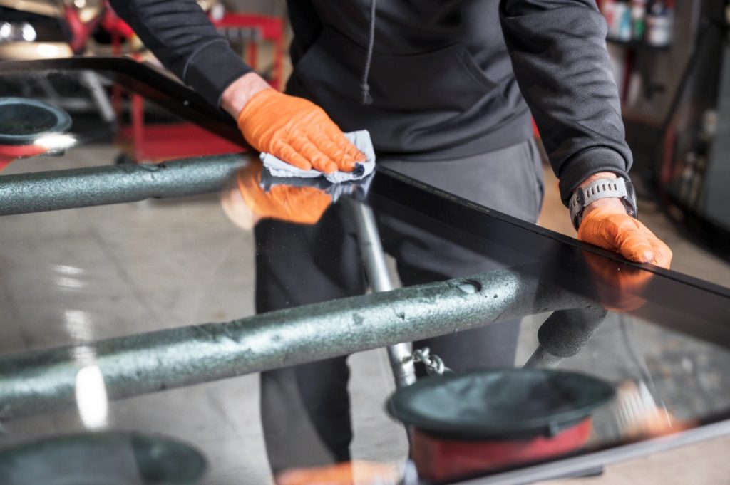 A technician preparing a windshield for auto glass replacement Baltimore, carefully cleaning the surface with a cloth.
