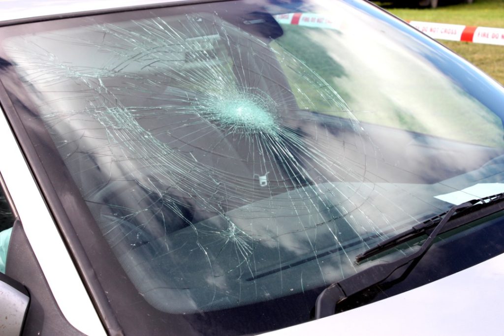 Large spiderweb crack on a silver car windshield requiring professional mobile windshield repair Baltimore experts.