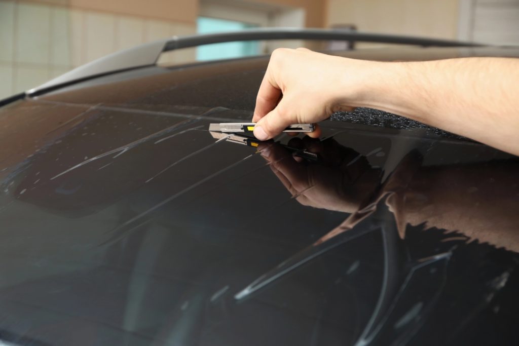 Expert applying tint film for a mobile auto glass repair Baltimore service to improve vehicle privacy and UV protection.