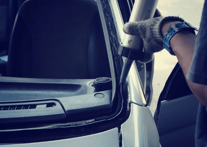 Close up of sealant application during a passenger windows repair Baltimore job to ensure a leak-proof car seal.