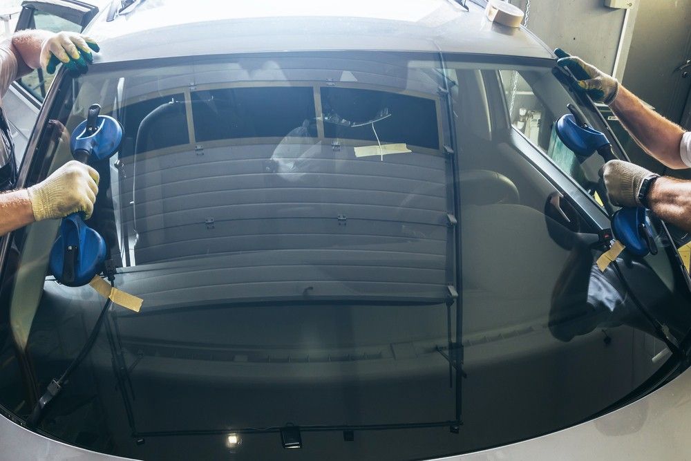 Expert car windshield fix Baltimore service: Technicians lower a new glass into place using specialized tools.