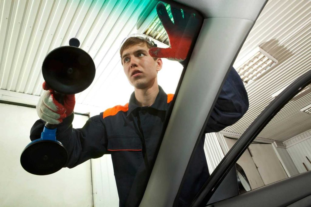 Technician handles auto glass replacement and repair Baltimore using heavy duty suction cups on a vehicle.