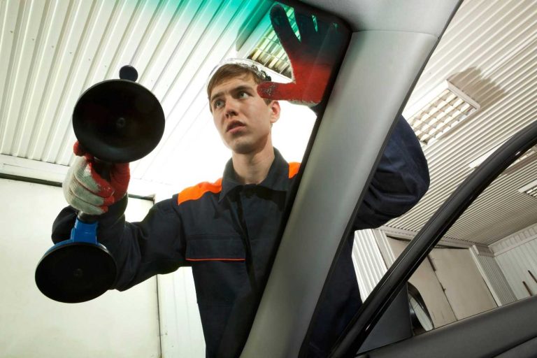 Technician handles auto glass replacement and repair Baltimore using heavy duty suction cups on a vehicle.