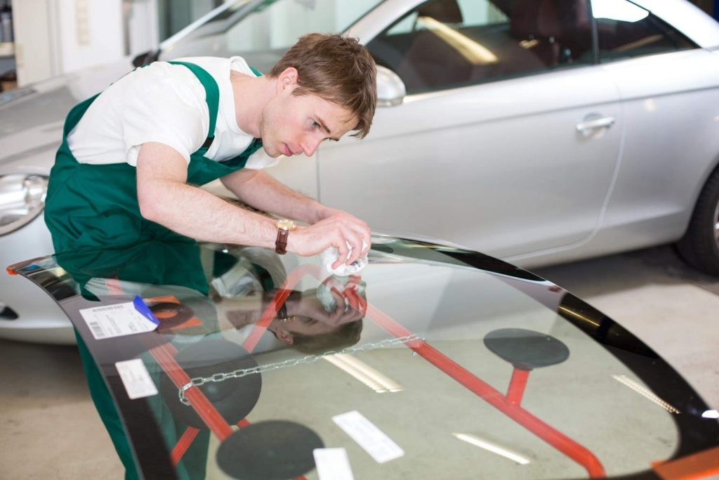 Auto glass shop Baltimore specialist carefully cleaning and prepping a brand new replacement windshield for install.