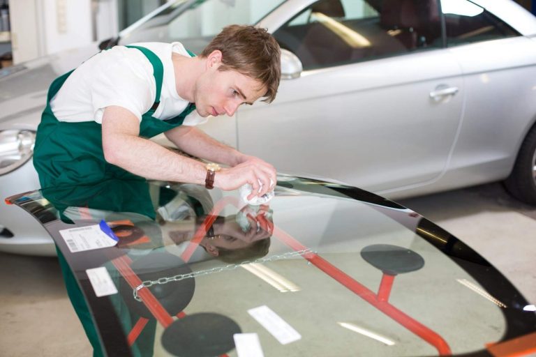 Auto glass shop Baltimore specialist carefully cleaning and prepping a brand new replacement windshield for install.