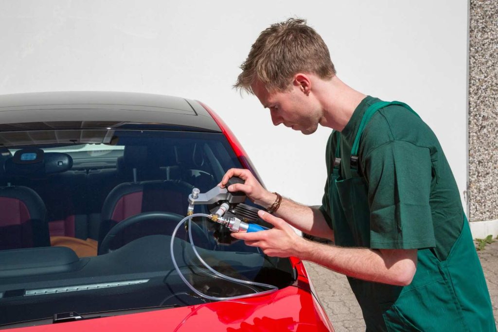 Technician at an auto glass shop Baltimore using specialized resin injection tools to repair a windshield crack.