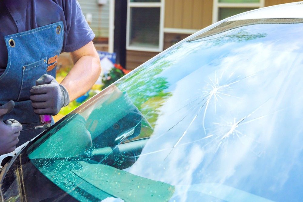 A mechanic in a denim apron uses a tool near multiple star cracks. We handle even severe damage with an Auto glass fix baltimore.