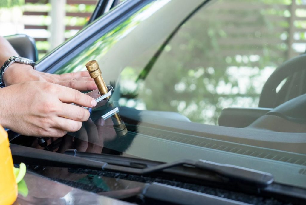 Technician at a windshield repair shop Baltimore fixing a glass chip with a professional bridge tool injection. 