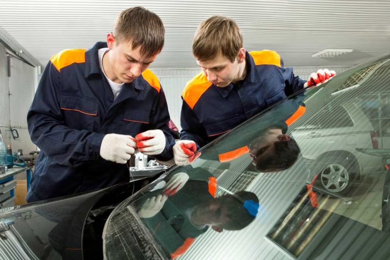 Auto glass technicians carefully sealing a car windshield during a mobile auto glass repair Baltimore project.