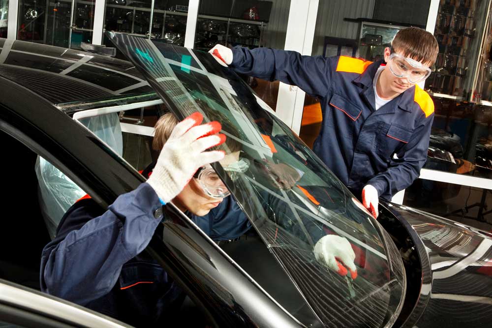 Two technicians installing a new windshield, providing professional mobile auto glass repair Baltimore services.